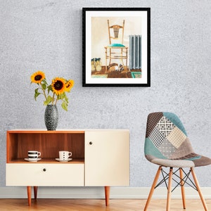 May include: A framed print of a vintage chair with a teal cushion, a radiator, and a pair of shoes on a wooden floor. The print is hanging on a light grey wall.