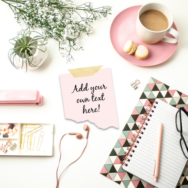May include: A pink notepad with a white lined page and a pink pen. The notepad is on a table with a pink and white geometric pattern. There is a pink stapler, a box of gold paper clips, a pink note with the text "Add your own text here!" and a pair of pink headphones on the table.