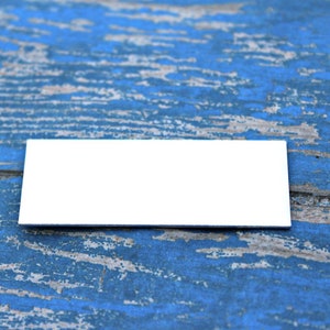 May include: A blank white rectangular card on a blue wooden surface with a distressed finish.