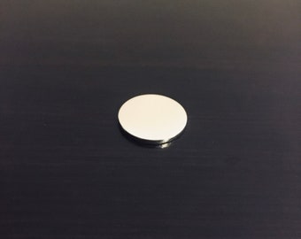 Puede incluir: Un disco redondo de color plateado con una superficie lisa.