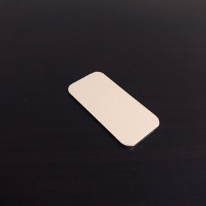 Puede incluir: Una etiqueta rectangular, lisa, plana, blanca, en blanco.