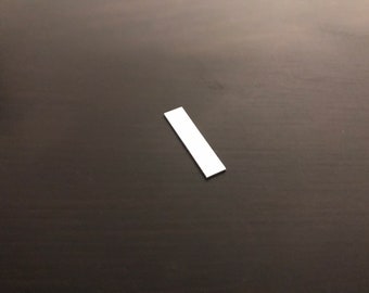 May include: A white rectangular piece of paper on a dark gray surface.
