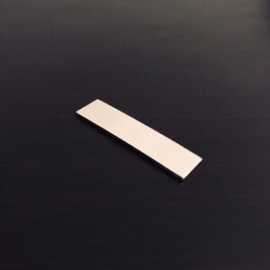 May include: A white rectangular magnet.
