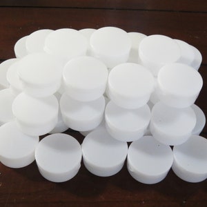 May include: A pile of white round plastic lids stacked on top of each other.