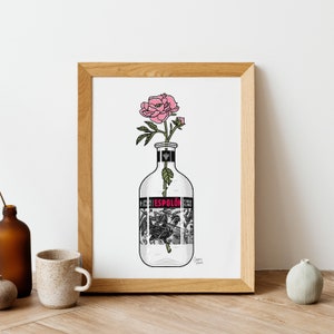 May include: A white framed print of a pink flower in a clear glass bottle with a black and white label that reads "Tequila Espolon Blanco".