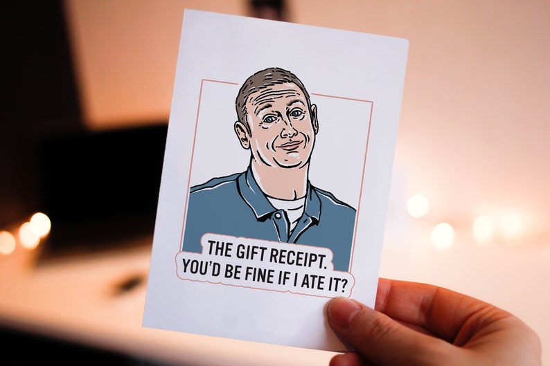 May include: A white card with a cartoon illustration of a man with a light blue shirt. The text on the card reads "THE GIFT RECEIPT. YOU'D BE FINE IF I ATE IT?"