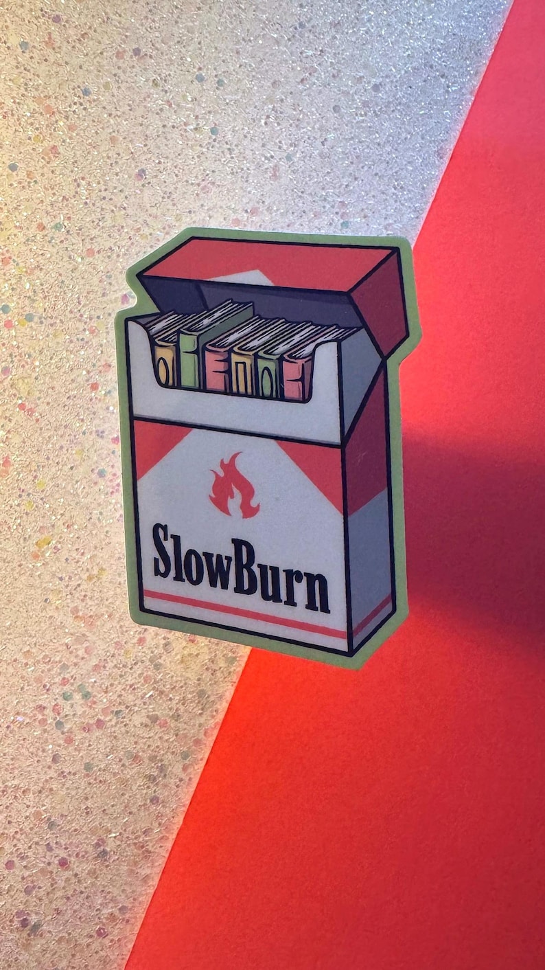 Puede incluir: Una pegatina con un dise&ntilde;o estilizado de un paquete de cigarrillos con la frase "SlowBurn" y un gr&aacute;fico de llama. El paquete es blanco con detalles rojos y contiene cigarrillos. La pegatina tiene un borde verde.