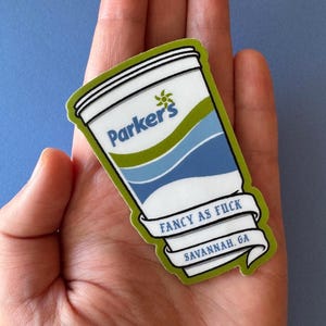 May include: A sticker featuring a stylized cup design with the text "Parker's" and "Fancy as Fuck Savannah, GA." The sticker has a white background with blue and green accents and a green border.