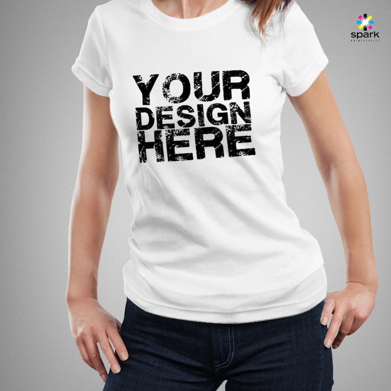 Pu&ograve; includere: Maglietta bianca con il testo "YOUR DESIGN HERE" stampato in nero.