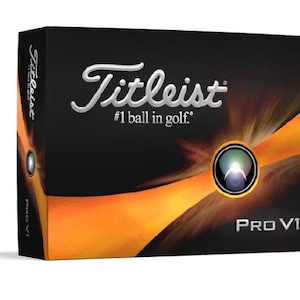 May include: A box of Titleist Pro V1 golf balls. The box is black with a gold and orange design. The Titleist logo is in silver and the text '#1 ball in golf' is below it. The words 'Pro V1' are in white on the bottom of the box.