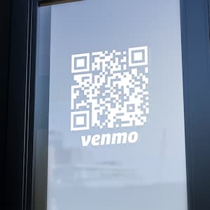 May include: A white QR code with the word "venmo" printed below it on a glass door.