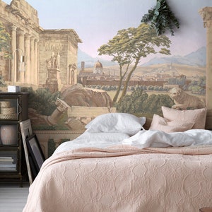 Op de afbeelding: Een roze gestikte bedsprei met witte linnen kussens op een bed voor een muurschildering die een oude Romeinse stad voorstelt.
