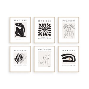 May include: Six minimalist art prints featuring black and white line drawings by Matisse and Picasso. The prints are framed in a light wood frame and have a white background. The prints include a seated figure, a floral design, a woman's head, a reclining figure, a stylized branch, and an abstract eye.