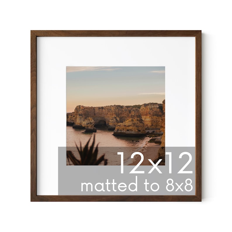 May include: A brown wood picture frame with a white mat, displaying a photograph of a rocky coastline at sunset. The frame is 12x12 inches and the matted image is 8x8 inches.