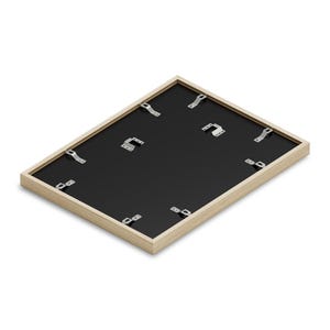 May include: The back of a light wood picture frame with a black mat and metal hanging hardware.