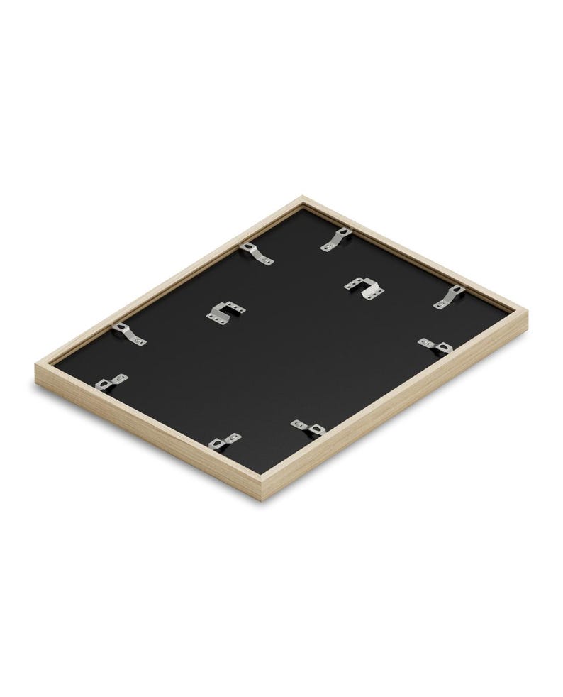 May include: The back of a light wood picture frame with a black mat and metal hanging hardware.