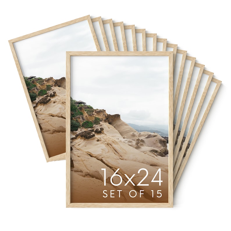 May include: A set of fifteen 16x24 inch framed prints. Each print features a landscape photograph of a rocky coastal area with beige rock formations, green vegetation, and a cloudy sky. The frames are made of light-colored wood.