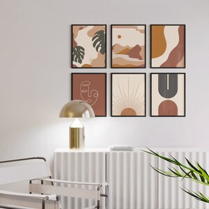 May include: A set of six framed abstract art prints in a minimalist style. The prints feature geometric shapes, line drawings, and organic forms in shades of brown, orange, and white. The prints are arranged in a grid pattern on a white wall.