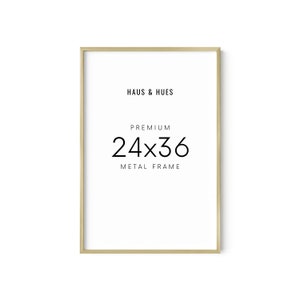 May include: Gold metal picture frame with the text "Haus & Hues" and "Premium 24x36 Metal Frame" printed on a white background.