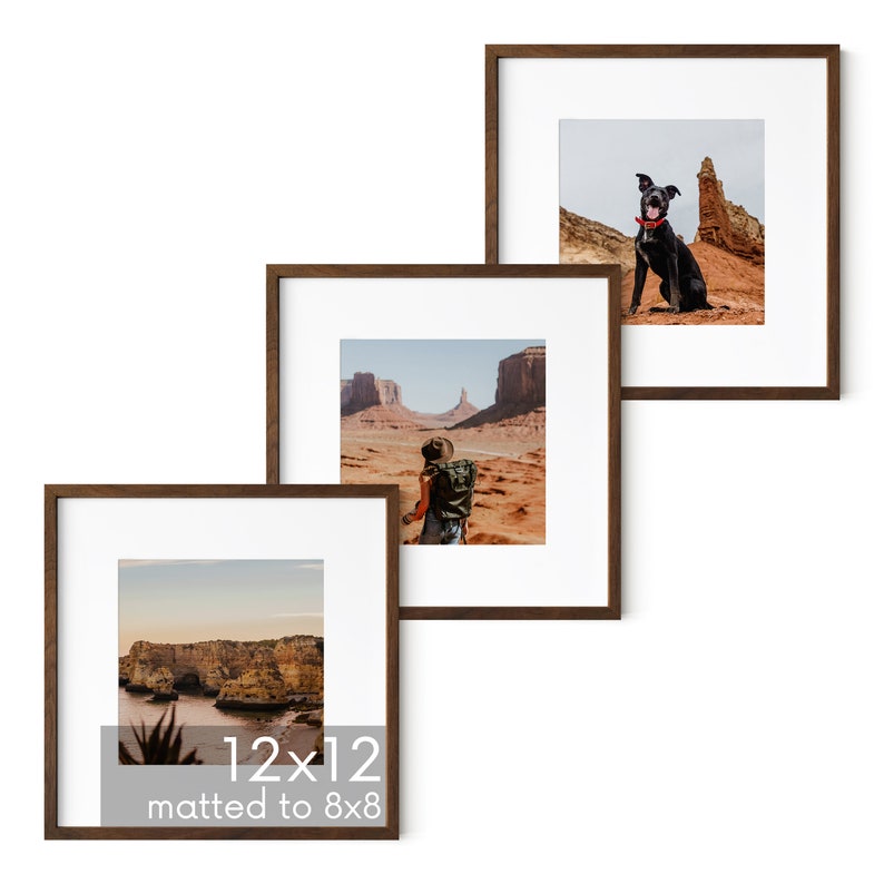 May include: Three brown wood picture frames with white mats. The frames are arranged in a staggered pattern. The top frame shows a black dog sitting on a red rock. The middle frame shows a person with a backpack standing in a desert landscape. The bottom frame shows a rocky coastline with a body of water in the background. The bottom frame has the text "12x12 matted to 8x8".