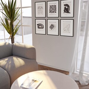May include: A set of six black framed prints with white line drawings of abstract shapes and figures. The prints are arranged in a grid pattern on a white wall. The prints are titled "Picasso" and "Matisse".