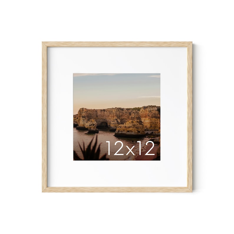 May include: A framed 12x12 inch print featuring a coastal landscape with rock formations and water. The print is set in a light wood frame with a white mat, creating a clean and natural aesthetic.