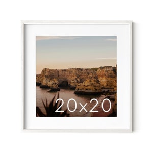 May include: A framed photograph of a rocky coastline with a blue sky and a body of water. The text "20x20" is printed in white on the image.