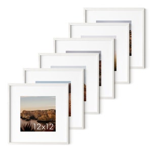 Op de afbeelding: Een set van zes witte fotolijsten, elk met een witte passe-partout, in een verspringende opstelling. De lijsten zijn 30,5 x 30,5 cm en bevatten verschillende landschapsfoto's.