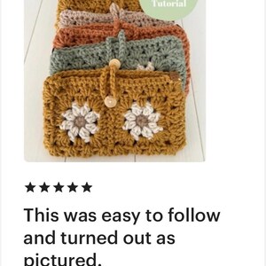 May include: A stack of five crocheted pouches in various colours, including mustard yellow, sage green, burnt orange, beige, and maroon. Each pouch features a white daisy design and a wooden button closure. The text "Cover Tutorial" is visible in a green circle.