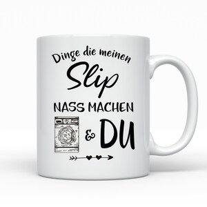 May include: White ceramic mug with a black design that says "Dinge die meinen Slip nass machen & DU" with a drawing of a washing machine and an arrow with hearts.
