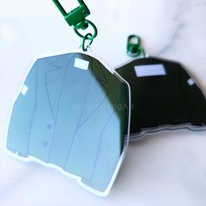 May include: Two clear acrylic charms featuring a green blazer and a black blazer. Both charms have a silver ring attached to the top.