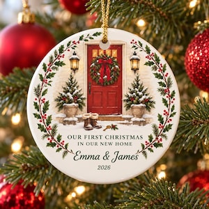 Può includere: Un addobbo natalizio rotondo in ceramica bianca raffigurante una porta rossa con ghirlanda, due alberi sempreverdi in vaso e stivali invernali. Testo: OUR FIRST CHRISTMAS IN OUR NEW HOME, Emma & James, 2026. Dotato di un cordino dorato.