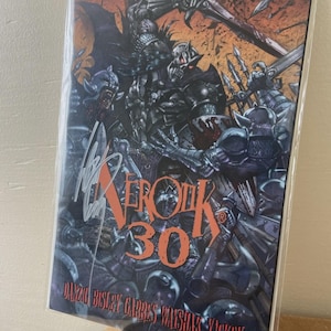 May include: Comic book titled "Xerox 30" featuring a detailed illustration of armored figures in a battle scene. The cover art is predominantly dark with accents of orange and red. The comic is signed and sealed in a protective plastic sleeve.