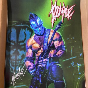 Puede incluir: Una fotografía en blanco y negro de un músico tocando una guitarra eléctrica negra. El músico lleva un atuendo blanco y negro y tiene la cara pintada de azul. El fondo es verde y borroso. La imagen está firmada "MOOSE" con tinta blanca.