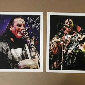 Puede incluir: Dos fotos en blanco y negro de músicos actuando en un escenario. La primera foto muestra a un hombre con una chaqueta de cuero negra y un diseño de calavera en su camisa, cantando en un micrófono. La segunda foto muestra a un hombre con una camisa roja y negra, cantando en un micrófono y tocando una guitarra. Ambas fotos están firmadas por los músicos.