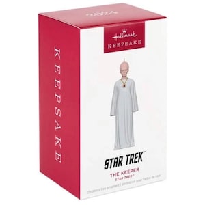 May include: A Hallmark Keepsake Star Trek Christmas tree ornament featuring The Keeper character. The figure is wearing a white robe and a gold necklace. The box is red and white with the text "2024" and "KEEPSAKE".