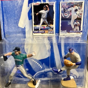 May include: A Starting Lineup baseball figure set featuring Randy Johnson and Nolan Ryan. The set includes two action figures and two baseball cards. The packaging includes the text "Classic Doubles of the Game's Greatest" and "1997 Edition".