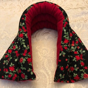 Op de afbeelding: Een rode en zwarte nekwarmer met een bloemenpatroon. De warmer is gemaakt van stof en heeft een zachte, pluche voering. Hij is ontworpen om te worden gebruikt als een warmtekussen voor nekverlichting.