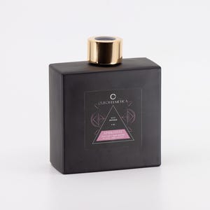 May include: A black glass bottle with a gold lid and a label that reads "OURCELLEMEDICA REED DIFFUSER APHRODISIAE OIL & AROMATHERAPY DIFFUSER BLEND".