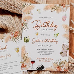 Puede incluir: Dos tarjetas de invitación con temática bohemia, con ilustraciones florales y de hierba de la Pampa. Las tarjetas anuncian un fin de semana de cumpleaños con el texto "Birthday Weekend" e "Itinerario de fin de semana". También hay un sello de cera dorado y una tela beige.