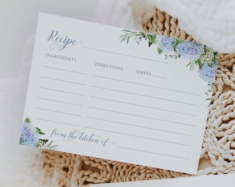 May include: Two white recipe cards with blue floral designs. The top card has the word "Recipe" written in cursive and has sections for ingredients, directions, and serves. The bottom card has the word "notes" written in cursive. Both cards have the text "from the kitchen of" written in cursive.