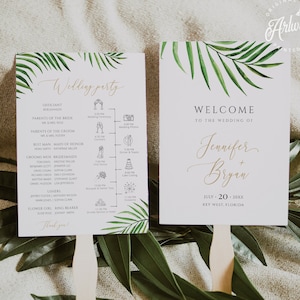 Pode incluir: Dois programas de leques de casamento brancos com texto dourado e detalhes de folhas de palmeira verdes. Um leque diz "Wedding Party" com uma programação da cerimônia. O outro diz "Welcome to the Wedding of Jennifer + Bryan."