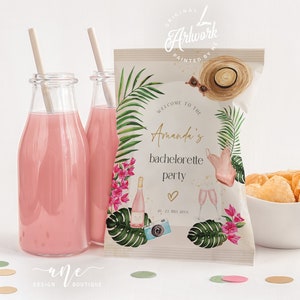 May include: A white paper bag with a tropical design featuring palm leaves, flowers, and a straw hat. The bag has text that says "Welcome to the Amanda's Bachelorette Party 20-21 July 20XX".