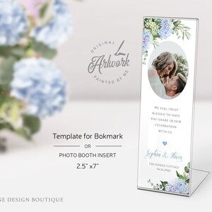May include: A template for a bookmark or photo booth insert featuring a watercolor illustration of blue hydrangeas and greenery. The template includes a space for a photo and text that reads "We feel truly blessed to have you share in our celebration with us, Sophia & Hiver, The Hidden Cottage, 06.26.20XX". The template measures 2.5 inches by 7 inches.