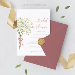 May include: A bridal shower invitation with a watercolour floral design. The invitation features the text "bridal shower" and other details in a delicate script. A mauve envelope and gold wax seal are included.