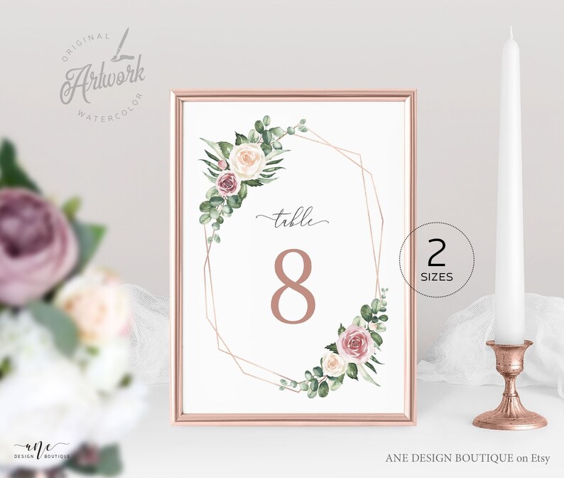 May include: A white table number card with a gold geometric frame and watercolor floral design. The card features the number 8 and the text "table".