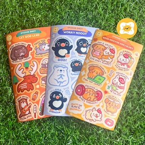 Op de afbeelding: Drie sticker vellen met kleurrijke illustraties en tekst. Eén vel heeft een beer, eland en otter met religieuze zinnen. Een ander heeft pinguïns en een ijsbeer met zinnen. De derde heeft cartoon dieren met religieuze thema's.