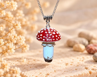 May include: A silver-toned metal chain necklace featuring a three-dimensional mushroom pendant. The mushroom cap is painted bright red with raised white spots, while the stem is a pale, light blue colour with a dark brown base.
