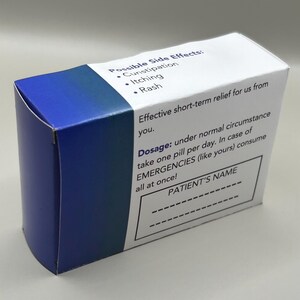 Op de afbeelding: Een blauwe en witte doos met de tekst "Possible Side Effects: Constipation, Itching, Rash" en "Dosage: onder normale omstandigheden &eacute;&eacute;n pil per dag innemen. In geval van NOODGEVALLEN (zoals die van u) alles in &eacute;&eacute;n keer innemen!" De doos heeft ook een lege ruimte voor de naam van de pati&euml;nt.
