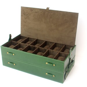 Puede incluir: Una caja rectangular verde para guardar relojes con tapa abatible y dos cajones. El interior est&aacute; forrado con tela marr&oacute;n y cuenta con doce compartimentos individuales, cada uno con una almohadilla para reloj de color marr&oacute;n.